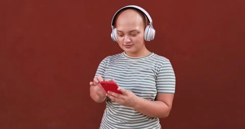 Young bald girl using mobile phone app to listening music playlist Stock Footage 161067122