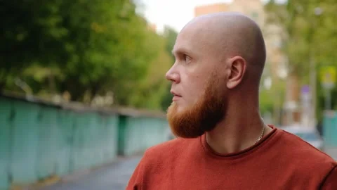 A young bald guy with a red beard looks thoughtfully around. Calm emotion. Stock Footage 139001725