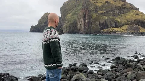 A young bald guy stands against the background in an Icelandic sweater Stock Footage 255785249