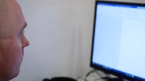 Young bald man at the computer typing, The big monitor, blinking Stock Footage 140450237