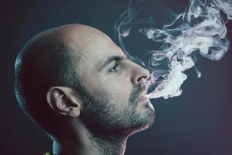 Young bald man exhaling cloud of smoke Stock Photos
