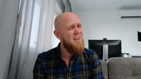 A young bald man with a red beard whimpers at the camera, wrinkling his face. Stock Footage 139194514