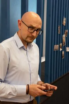 Young bald man using his mobile phone, texting or preparing call Stock Photos