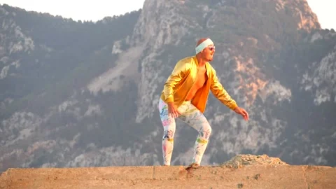 Young bald slender freak man in tight leggings, gold jacket, bandage Stock Footage 138933322