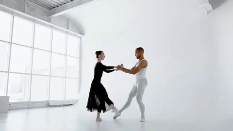 Young ballet dancer gently holds the brunette ballerina during the dance near Vídeos de archivo 77219737
