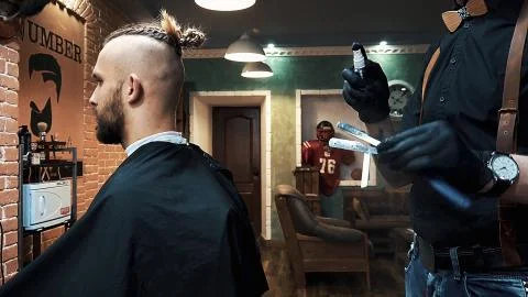 Young barber doing haircut with clipper in the barbershop. Stock Photos