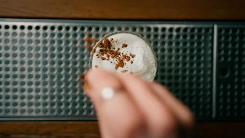 Young bartender adds cinnamon and garnishes to the Coconut Paradise cocktail at Vidéo 240444644