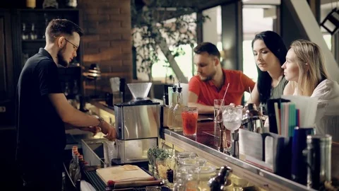 The young bartender adds ice to the cocktail in order to cool it a company of Stock Footage 78000862