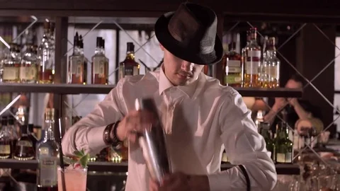 Young bartender in a hat shakes a shaker in the bar close-up slow motion. Stock Footage 76721785