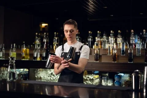 A young bartender hosts a show with shakers at the bar in a nightclub Stock Photos