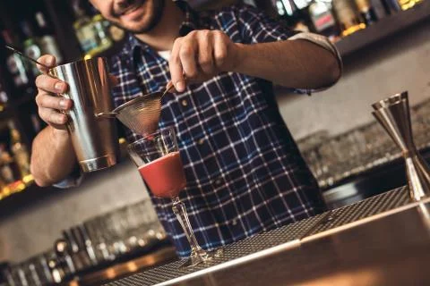 Young bartender standing at bar counter making cocktail cheerful Stock Photos