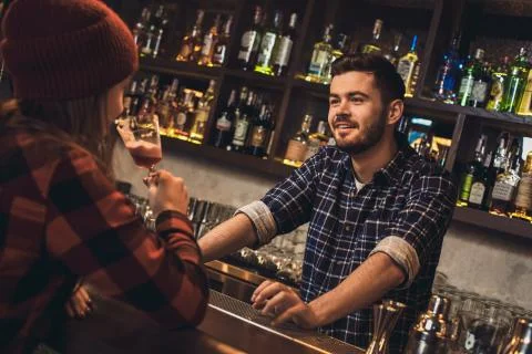 Young bartender standing at bar counter talking with girl joyful Stock Photos