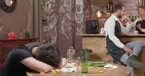 Young bartender tries to wake a drunk customer Stock Footage 104868387