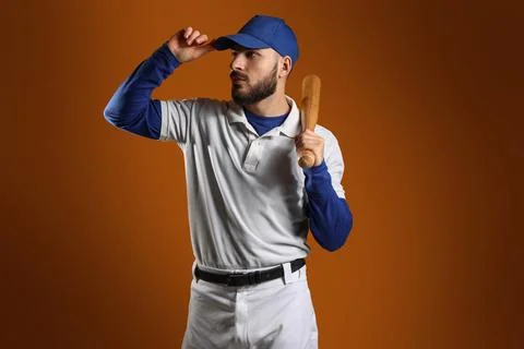 Young baseball player in white uniform and blue cap holding bat, ready for ga Stock Photos
