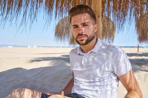 Young beard man in a beach under parasol Stock Photos