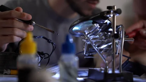 Young bearded apprentice in glasses working with soldering iron at his working Stock Footage 113692452
