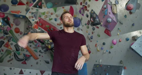 Young bearded athlete warming up before training on climbing wall Stock Footage 131327153