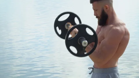 Young bearded athletic bodybuilder plays sports outdoors. Weightlifter Stock Footage 120071993