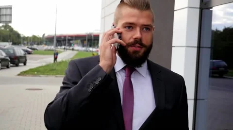 Young bearded businessman using mobile phone outside the office Stock Footage 56526464