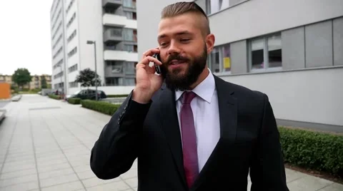 Young bearded businessman using mobile phone outside the office Stock Footage 56526601