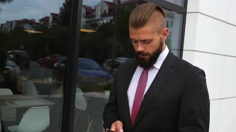Young bearded businessman using mobile phone outside the office Stock Footage 60945227