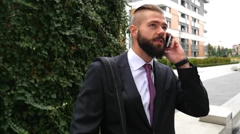 Young bearded businessman using mobile phone outside the office Stock Footage 60945256