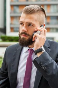 Young bearded businessman using mobile phone outside the office. Outdoor phot Stock Photos