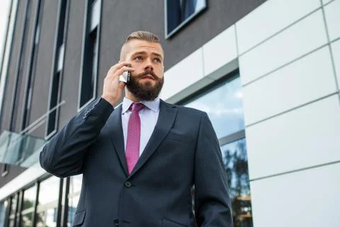 Young bearded businessman using mobile phone outside the office. Outdoor phot Stock Photos