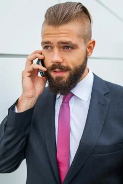 Young bearded businessman using mobile phone outside the office. Outdoor phot Stock Photos
