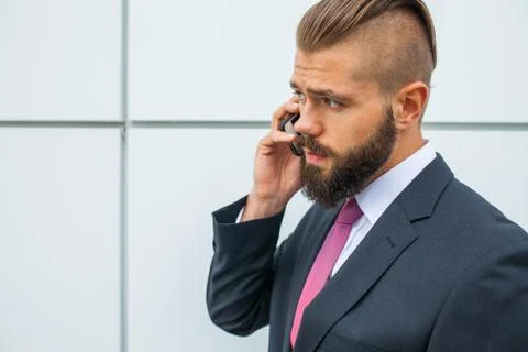 Young bearded businessman using mobile phone outside the office. Outdoor phot Stock Photos