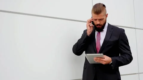 Young bearded businessman using tablet pc and mobile phone. Outdoor photo. Stock Footage 56526460