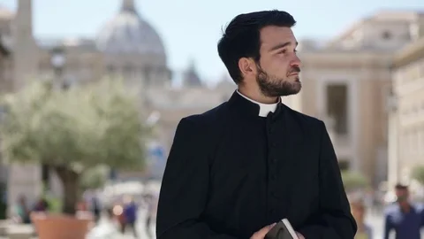  Young bearded Catholic priest scrolls the Bible and smiles at the camera Stock Footage 76458570