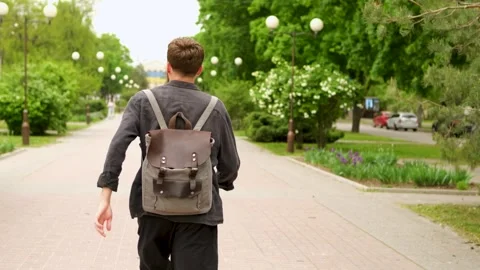 A young bearded Caucasian guy with a backpack on his back is running Stock Footage 279742375