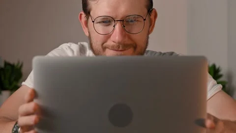 Young bearded caucasian man in computer glasses works on laptop at home. Student Stockbeeldmateriaal 198478798