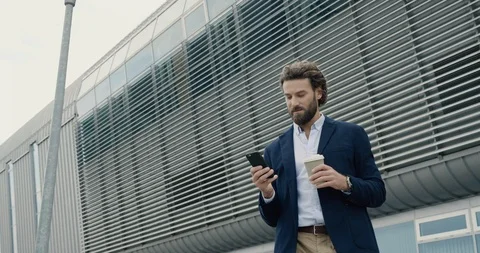 Young bearded Caucasian Man is standing near Industrial Building with Phone. Stock Footage 124017853