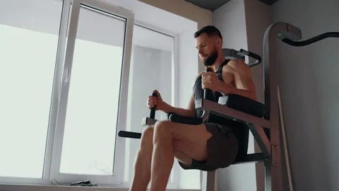 The young, bearded coach shows how to perform, raising his legs up to work a Stock Footage 156865151