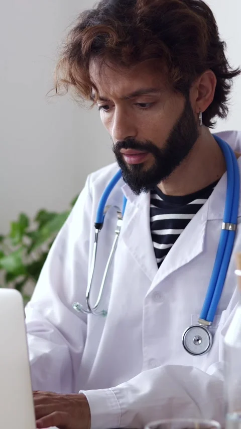 Young bearded doctor man using laptop computer on medical consultation office Stock Footage 284891894