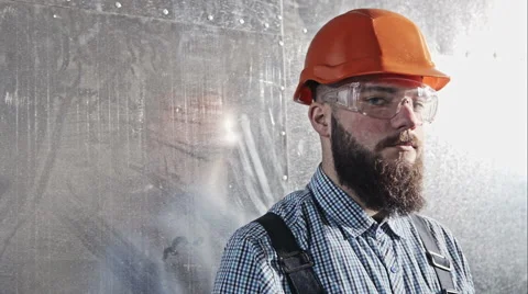 Young bearded engineer builder in a protective helmet and goggles on background Stockbeeldmateriaal 61111461