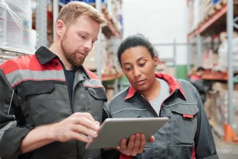 Young bearded engineer or worker of warehouse and his colleague using tablet 스톡 사진
