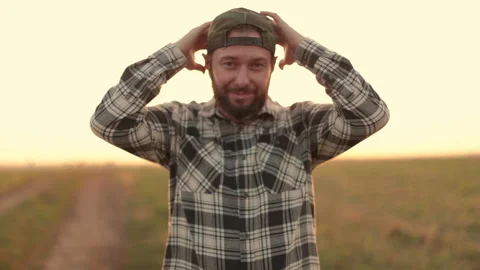 A young bearded farmer puts on a cap. Stock Footage 265551060