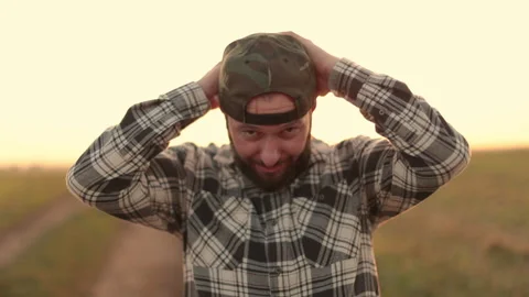 A young bearded farmer puts on a cap. Stock Footage 265551502