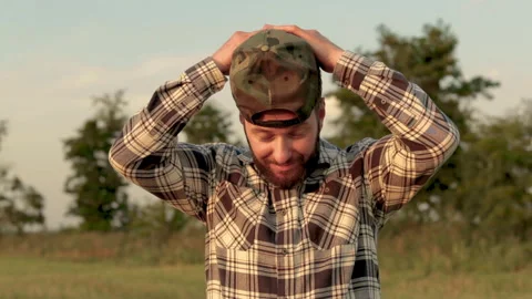 A young bearded farmer puts on a cap. Stock Footage 265552116