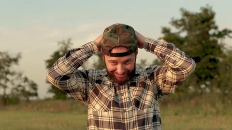 A young bearded farmer puts on a cap. Stock Footage 265552438