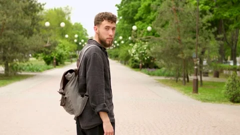 A young bearded guy with a backpack turns around Stock Footage 279742036