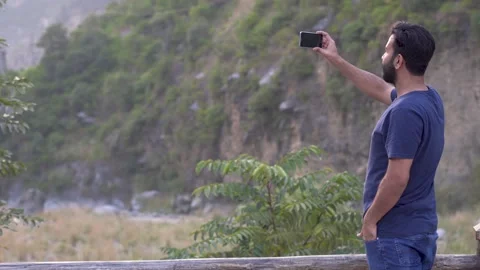 Young bearded guy capturing landscape with mobile phone Stock Footage 140287087