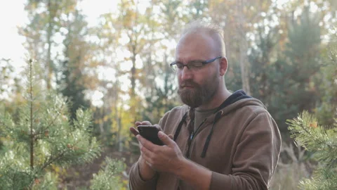 Young, bearded guy holding a phone and presses the screen Video stock 100724105