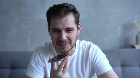 Young bearded guy sitting on couch and smiling while talking on mobile phone Stock Footage 137971341