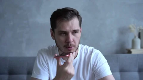 Young bearded guy sitting on couch and smiling while talking on mobile phone Stock Footage 137971354