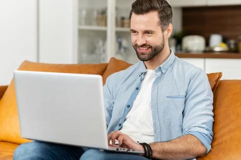 Young bearded hipster guy is typing on the laptop Stock Photos