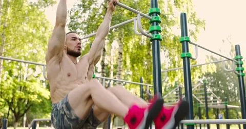 Young bearded man with a bare torso doing leg lifting on a horizontal bar on Video stock 157562685